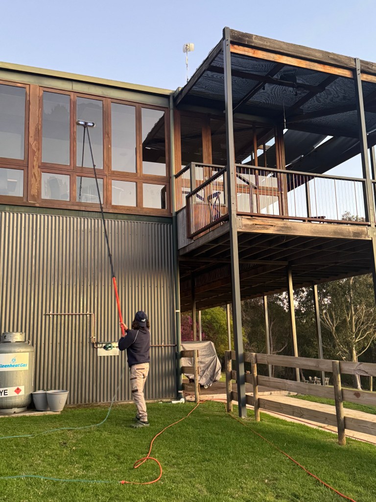 Window cleaner washing tall building with extendable pole